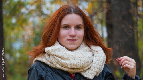 portrait of a red - haired smiling girl in a jacket smiling . against the background of autumn nature, the concept of human emotion