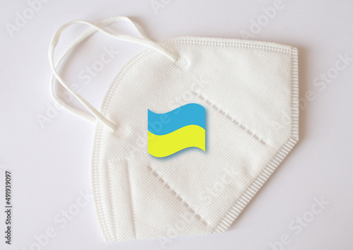 Supplemented symbol of the Ukrainian flag on a white medical mask, filter. Quarantine during the coronavirus pandemic COVID-19 in Ukraine. Symbolic supporting object of peace. photo