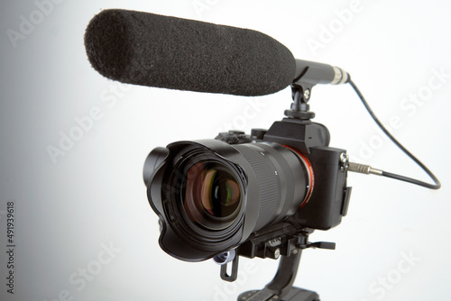 mirrorless camera and a connected microphone mounted on an electronic stabilizer on a white background
