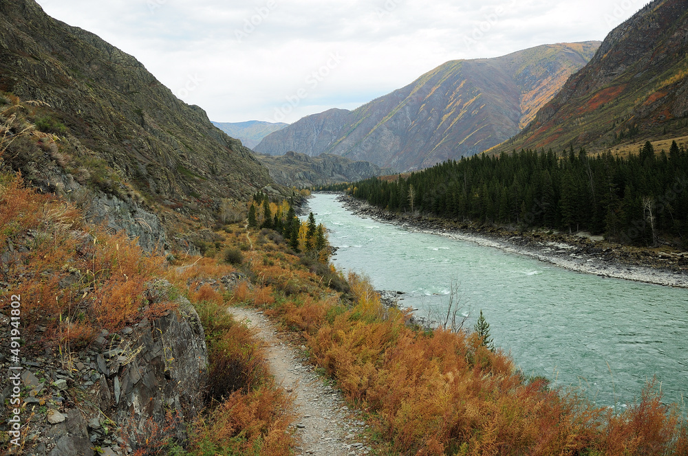The path along the mountainside along the flowing beautiful turquoise river in the mountains.