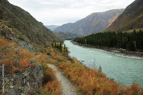 The path along the mountainside along the flowing beautiful turquoise river in the mountains.