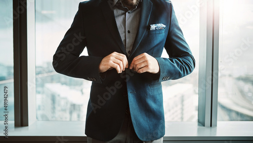 Success just got real. Cropped shot of a stylish businessman button his jacket in a modern office.