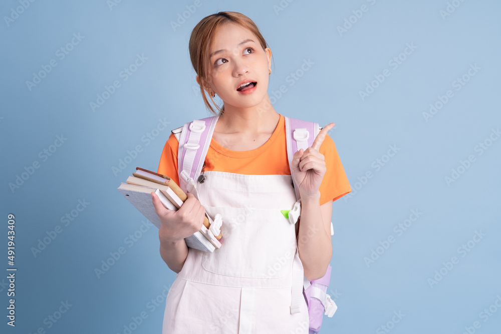 Young Asian student posing on blue background Young Asian student posing on blue background