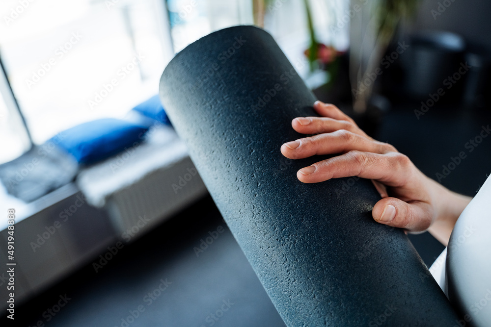 Close-up yoga mat. Blue is a soft element of sports equipment. the hand holds the yogamate rolled up in a roll.