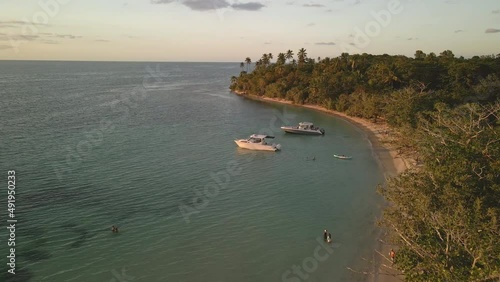 Flying drone over boats in crystal clear blue waters during sunset. photo