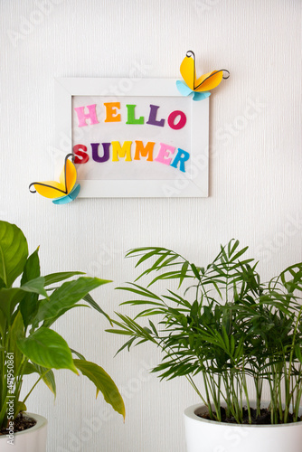 White photo frame decorated with paper butterflies. Flowers and crafts in the interior.