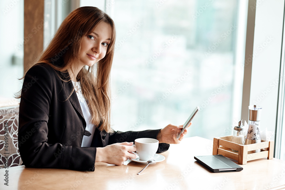 Young business woman using her smart phone and smiling in coffee shop Young business woman using her smart phone and smiling in coffee shop
