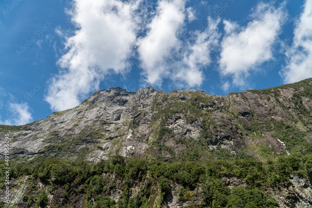 Top of Majestic Sheer Rock Face of a Mountain Rising Up to a Cloudy Sky On a Sunny Day