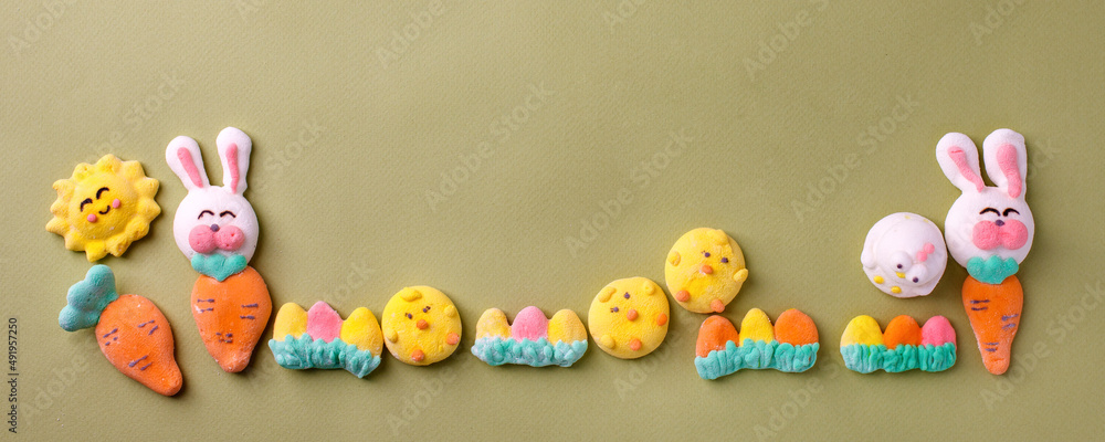 Fototapeta premium Happy Easter concept. Preparation for holiday. Easter marshmallow candy chiken, rabbit, carrot, bunny on green pastel background. Simple cute, funny minimalism flat lay top view, copyspace banner