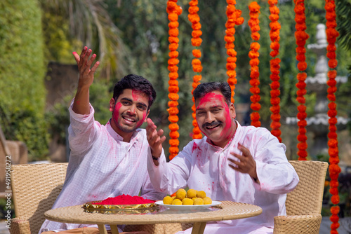 Portrait of father and son with colourful face celebrating Holi  photo