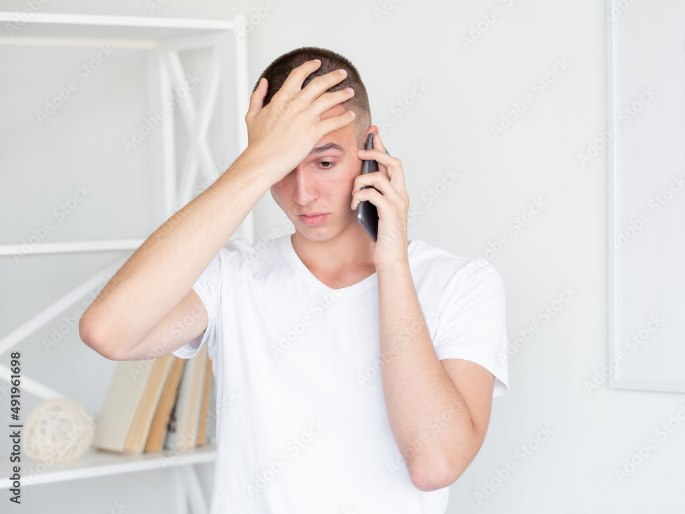 Shocked news. Disbelief man. Mobile communication. Embarrassed guy expressing epic fail talking smartphone in light room interior. Shocked news. Disbelief man. Mobile communication. Embarrassed guy expressing epic fail talking smartphone in light room interior.