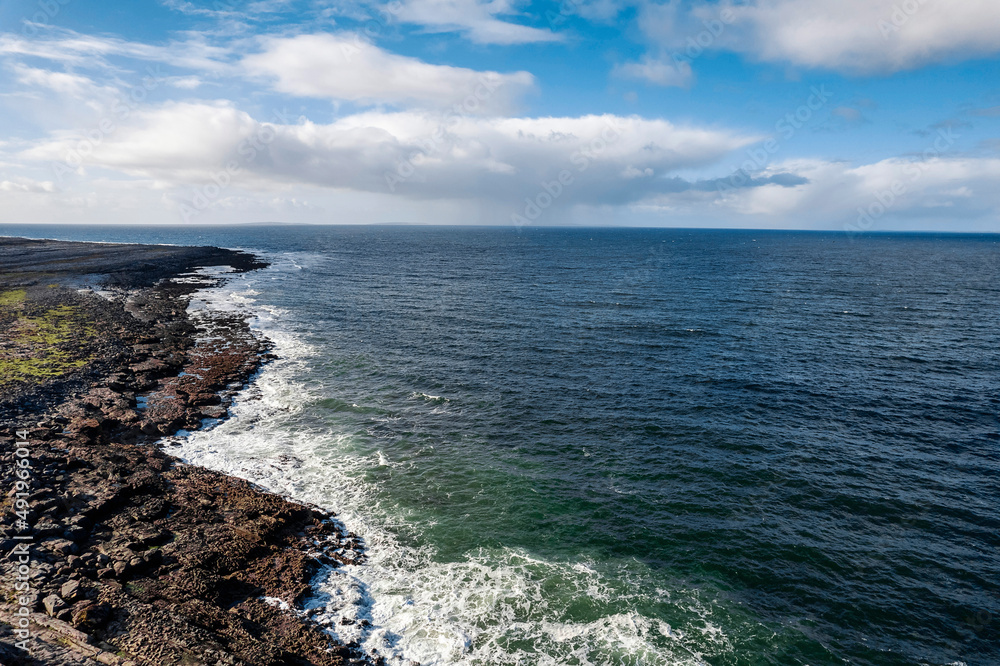 Rough stone coastline and blue ocean surface, cloudy sky. West coast of Ireland. Burren area. Nobody. Aerial view.