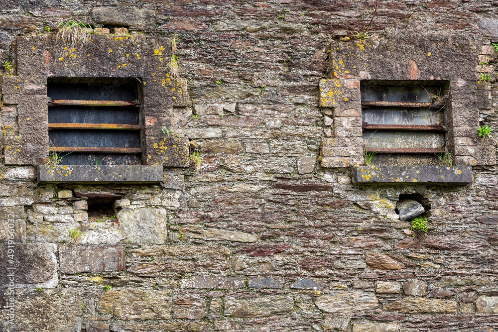 Two small jail windows with metal bars. Law correction facility with hard living condition. Stone wall, history prison. Two small jail windows with metal bars. Law correction facility with hard living condition. Stone wall, history prison.