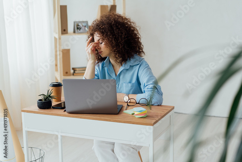 Young curly woman work on the notebook  drink coffee and having stress. Work space