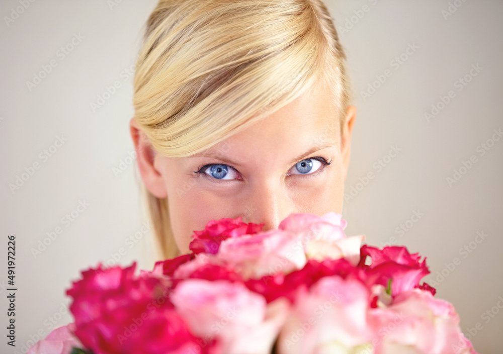 Another present from her secret admirer. Portrait of a young woman peering over a bouquet of pink roses. Another present from her secret admirer. Portrait of a young woman peering over a bouquet of pink roses.