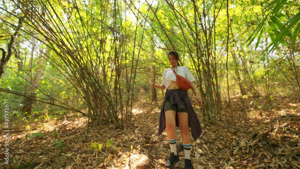 Young woman hiker walking along a path in tropical rainforest bamboo jungle. High quality 4K nature footage. Thailand. Young woman hiker walking along a path in tropical rainforest bamboo jungle. High quality 4K nature footage. Thailand.