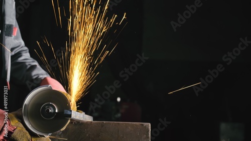 Forge workshop. Smithy manual production. Close up details of sparks, industrial worker using angle grinder and cutting steel. The blacksmith makes iron products for manufacture of fireplaces, stoves. photo