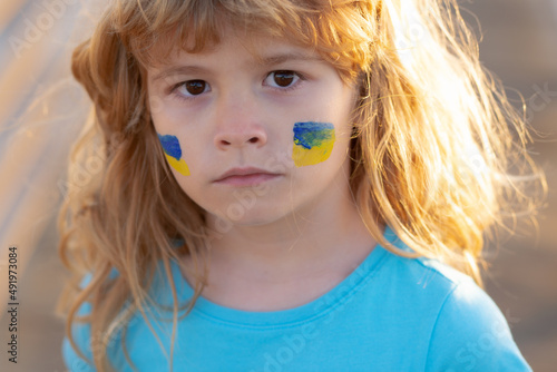 Ukraine flag on kids cheek. No war, stop war, russian aggression. Little ukrainian patriot.
