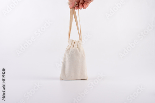 Hand and small fabric pouch isolated on white background.