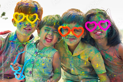 Obraz na plátne Group of Cheerful kids with fun spectacles Shouting at camera after playing with colourful holi powder during festival celebration