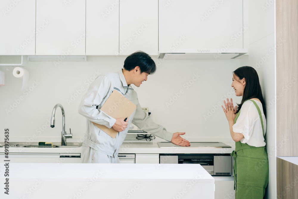 Fototapeta premium キッチンで話す作業着姿の男性と女性(IH・笑顔)