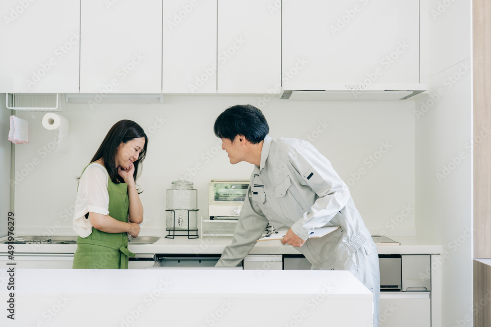 Fototapeta premium キッチンで話す作業着姿の男性と女性（食洗機） 