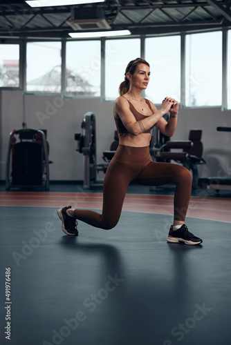 Pretty woman working out in a gym. Adult pretty sporty lady with beautiful shaped body.