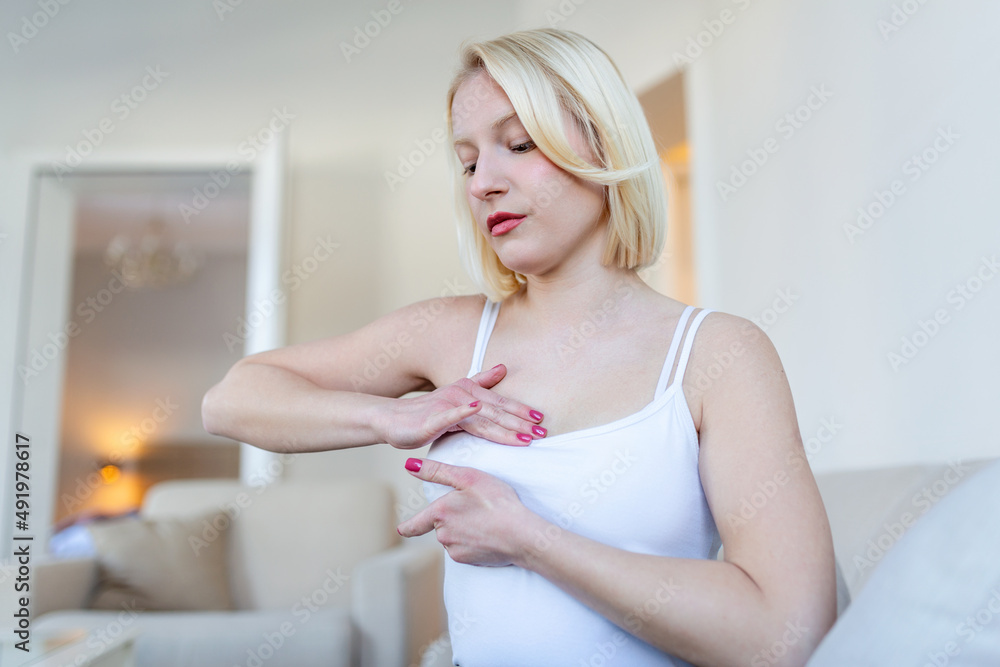 Young caucasian woman palpating her breast by herself that she concern about breast cancer. Healthcare and breast cancer concept Young caucasian woman palpating her breast by herself that she concern about breast cancer. Healthcare and breast cancer concept