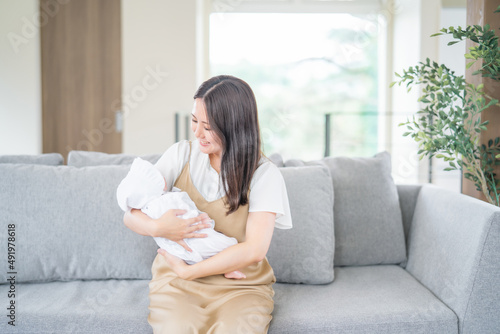 ソファーで赤ちゃんを抱っこする女性 