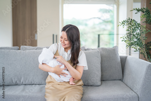 ソファーで赤ちゃんを抱っこする女性 