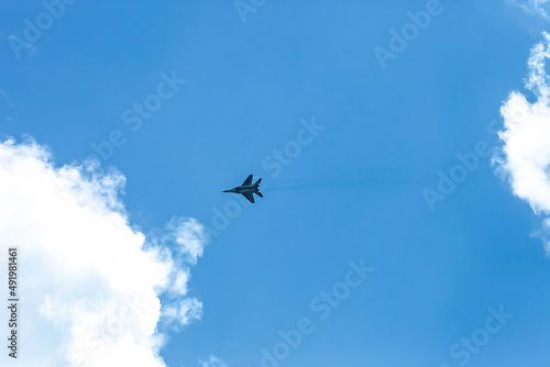 Fast Fighter flying high in blue sky background. Supersonic airplane silhouette flight in air at distance