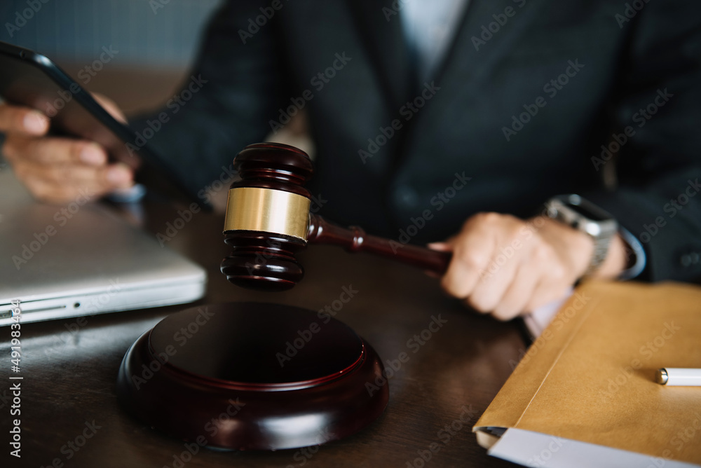 Auction hammer on the desk in lawyer office and lawyer writing document as courtroom. Auction hammer on the desk in lawyer office and lawyer writing document as courtroom.
