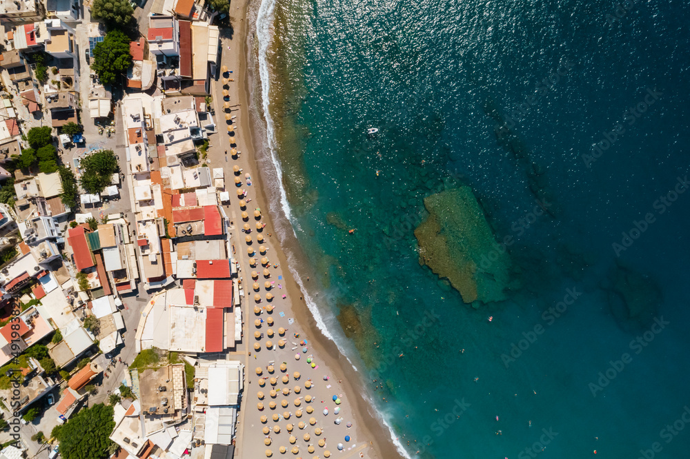 Ujęcie z drona na piękną plażę w Matala, na wyspie Kreta w Grecji, turkusowa woda i pomarańczowy piasek, rzędy parasoli plażowych - obrazy, fototapety, plakaty 