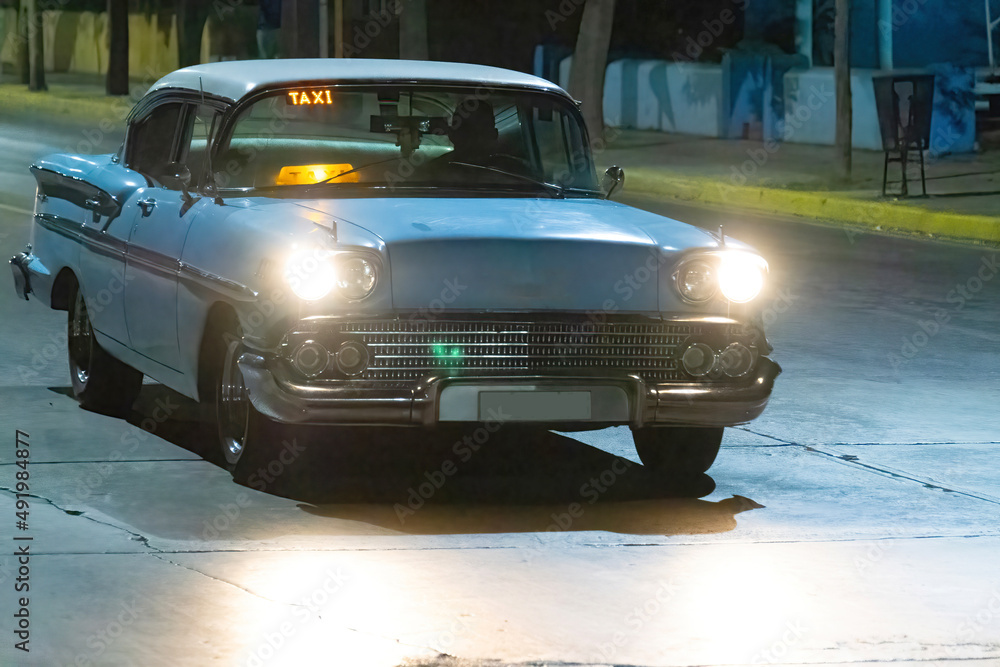 Vintage American car driving at night in Varadero, Cuba Stock Photo