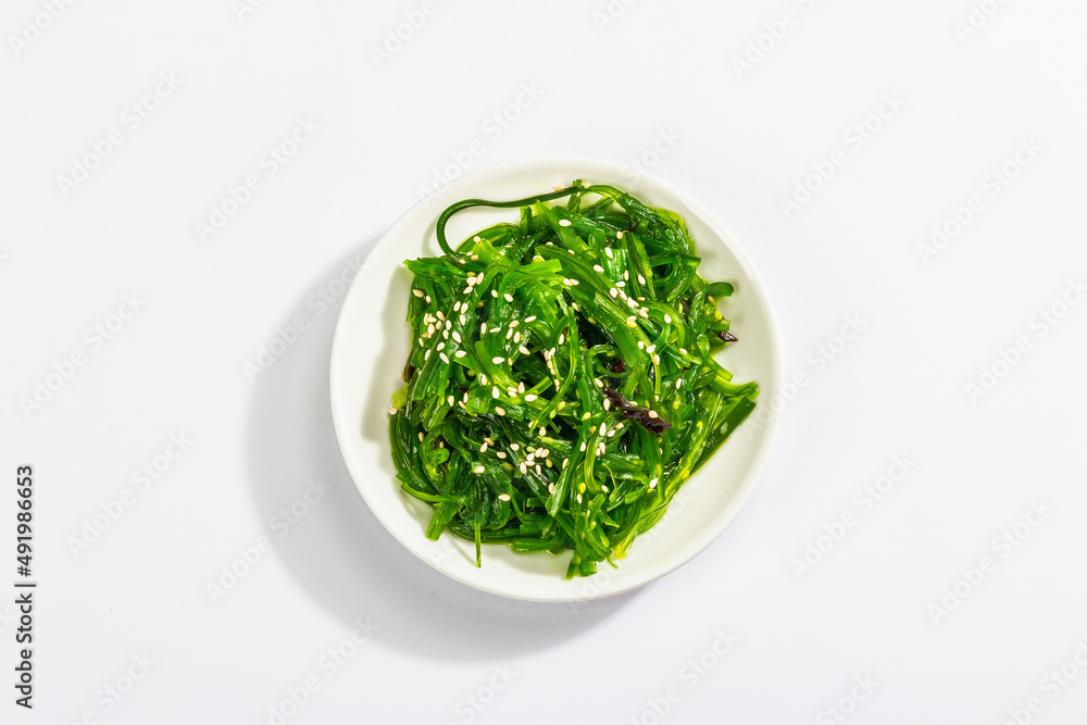 Chuka Seaweed Salad with sesame seeds isolated on white background. Trendy hard light, dark shadow Chuka Seaweed Salad with sesame seeds isolated on white background. Trendy hard light, dark shadow