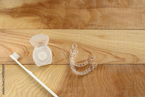 Toothbrush, mouthpiece and dental floss on a wooden table