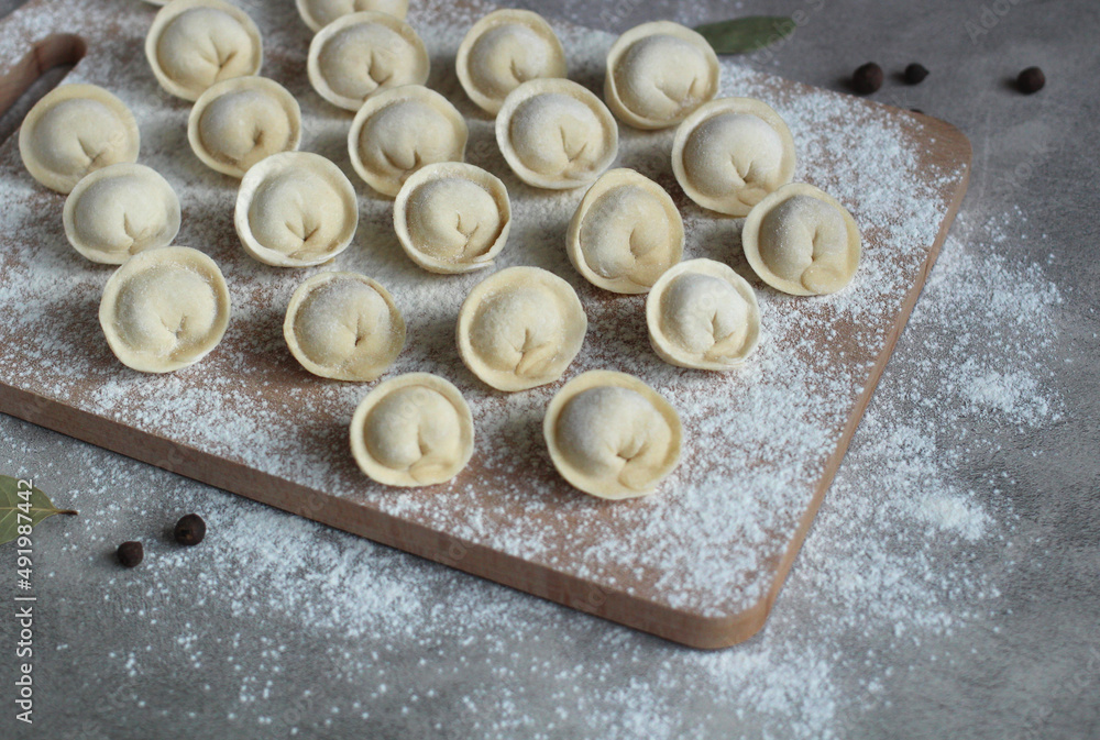 homemade dumplings on a cutting board in rows of flour, pepper and bay leaf homemade dumplings on a cutting board in rows of flour, pepper and bay leaf