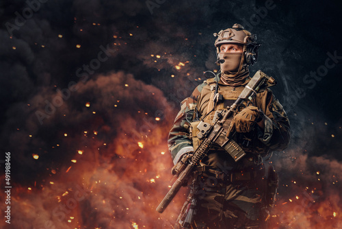 Fotografiet Military soldier dressed in uniform with rifle against flame