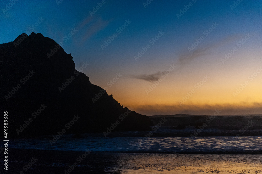 Bright orange sky at Pfeiffer beach, around sunset. Small crescent moon is in the background.