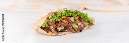 Döner Kebab Doner Kebap slice fast food in flatbread on a wooden board panorama
