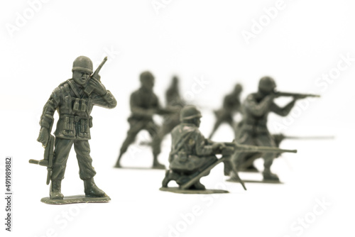 Plastic toy soldiers are arranged in a conflict situation and set against a white background.  photo