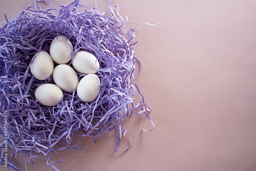 white eggs in a paper nest top view on a pink background, empty space white eggs in a paper nest top view on a pink background, empty space