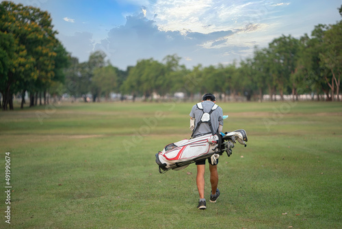 boy golfer walking with his golf bag on the fairway
