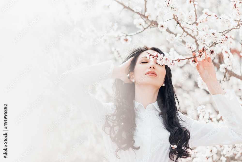 Portrait of pretty brunette girl posing against the spring blooming trees in the garden. Portrait of pretty brunette girl posing against the spring blooming trees in the garden.