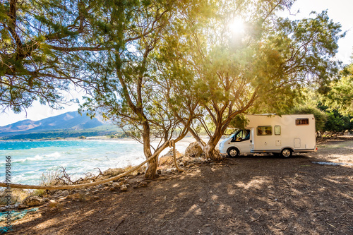 Motorhome RV parked on the beach under a tree facing the sea, Crete, Greece.