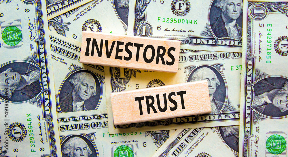 Investors trust symbol. Concept words Investors trust on wooden blocks on a beautiful background from dollar bills. Business invest and investors trust concept, copy space.