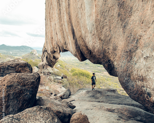 turista caminhando com montanhas ao fundo na Pedra Furada, em Venturosa, Pernambuco