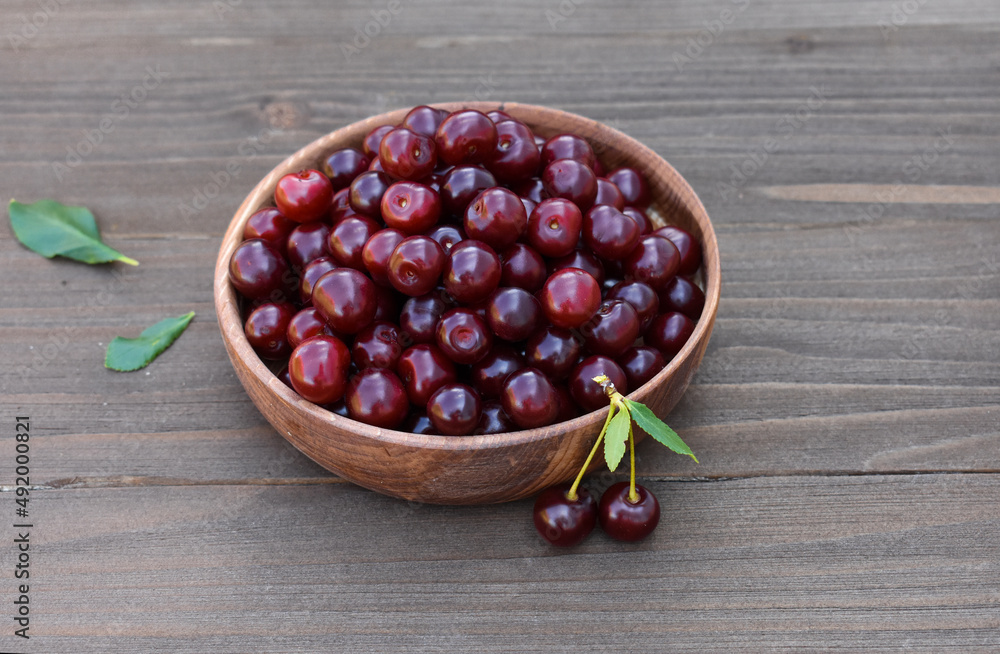 cranberries in a bowl,red cherries in a wooden bowl on an old wooden background cranberries in a bowl,red cherries in a wooden bowl on an old wooden background