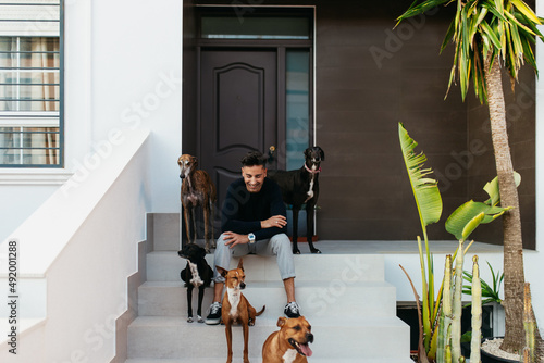 Photography Happy pet owner sitting on the porch with his dogs