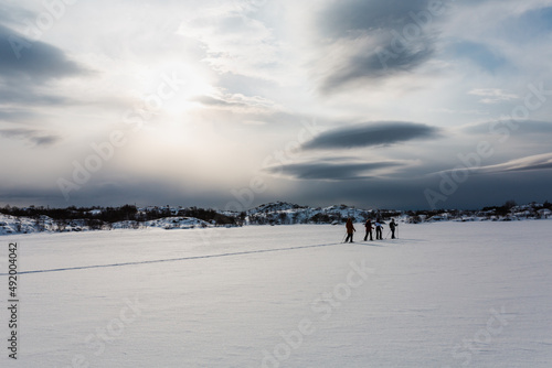 ślady na śniegu, turyści zwiedzają piękne Lofoty w Norwegii, ośnieżone góry i zamarznięte jeziora